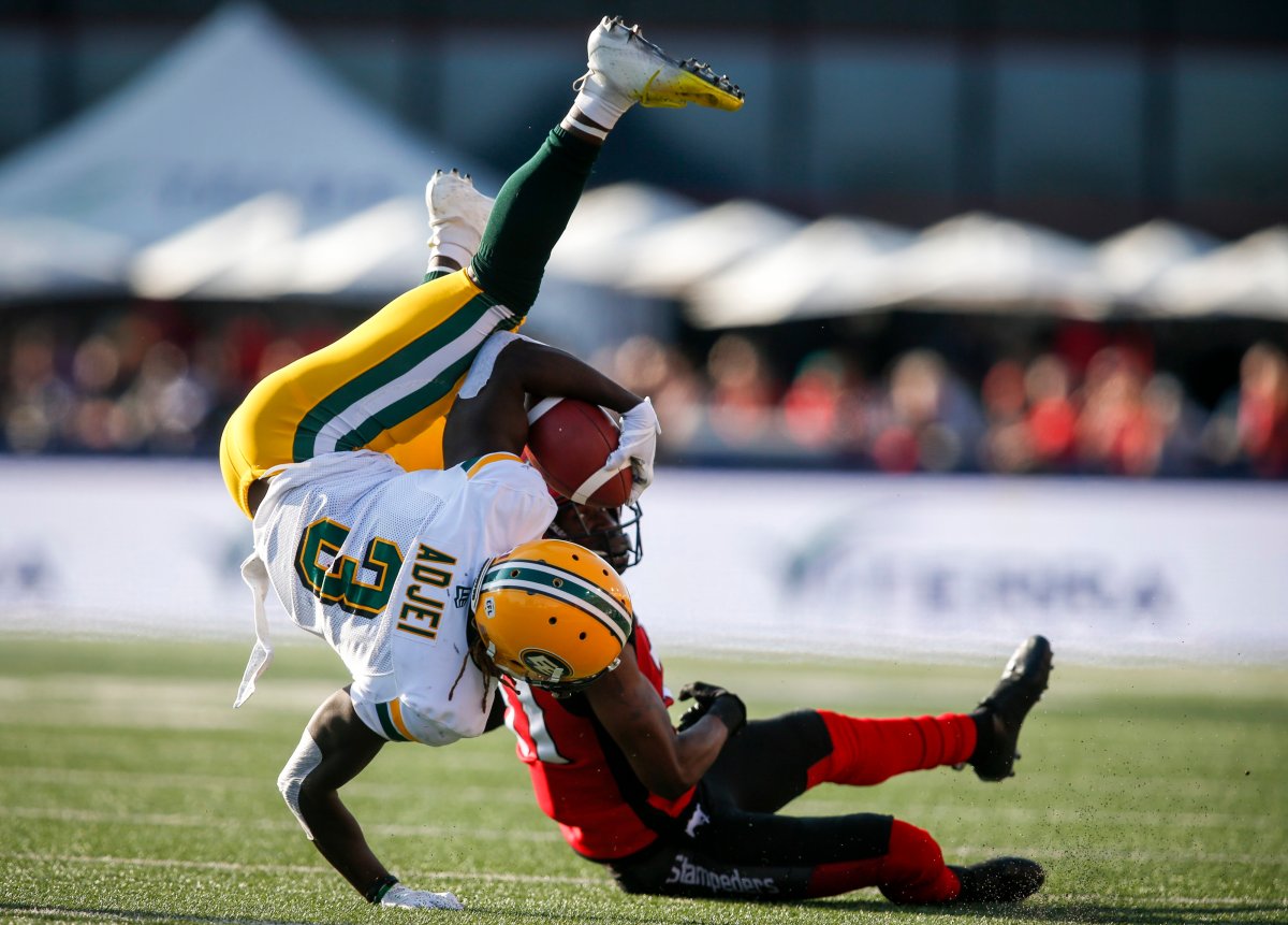 Edmonton Eskimos' Natey Adjei, left, is upended by Calgary Stampeders' Tre Roberson during second half CFL football action in Calgary, Saturday, Aug. 3, 2019. 