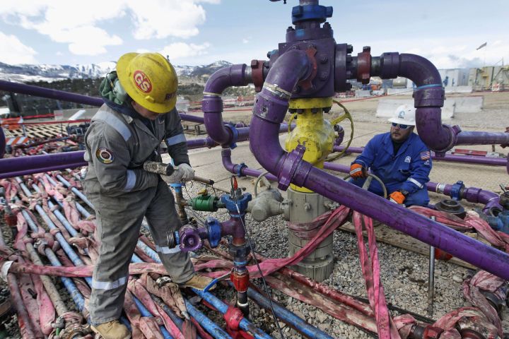 Canada's two biggest publicly traded oil and gas well fracking companies are posting double-digit percentage revenue declines as energy exploration spending slowed in the quarter ended June 30. Workers tend to a well head during a hydraulic fracturing operation outside Rifle, in western Colorado, March 29, 2013. 