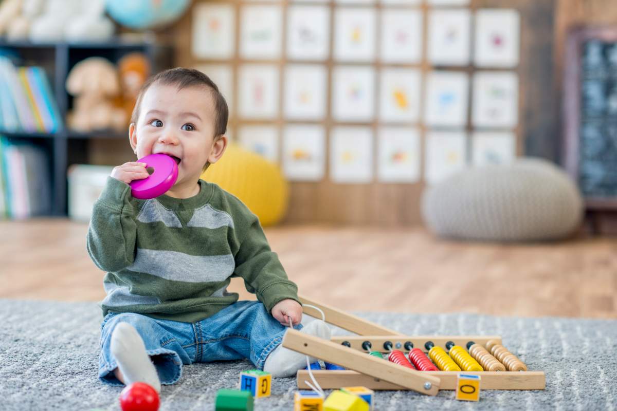 A young boy sitting on the carpet in a day care centre.