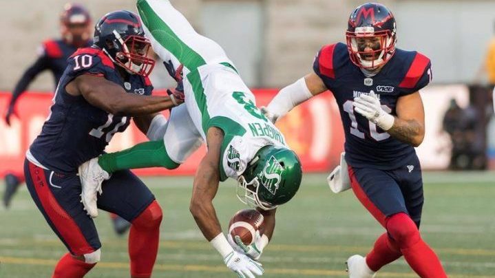 Saskatchewan Roughriders' Marcus Thigpen, centre, flips over as Montreal Alouettes' Henoc Muamba, left, as Taylor Loffler looks on during first half CFL football action in Montreal, Friday, August 9, 2019. THE CANADIAN PRESS/Graham Hughes.