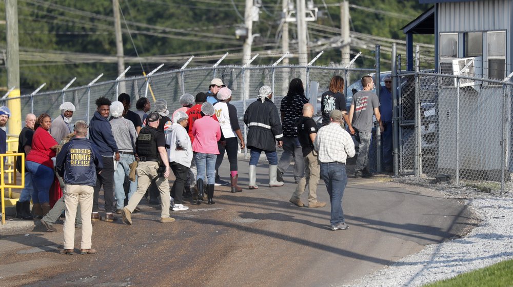 Handcuffed female workers are escorted into a bus for transportation to a processing centre following a raid by U.S. immigration officials at a Koch Foods Inc., plant in Morton, Miss., Wednesday, Aug. 7, 2019.