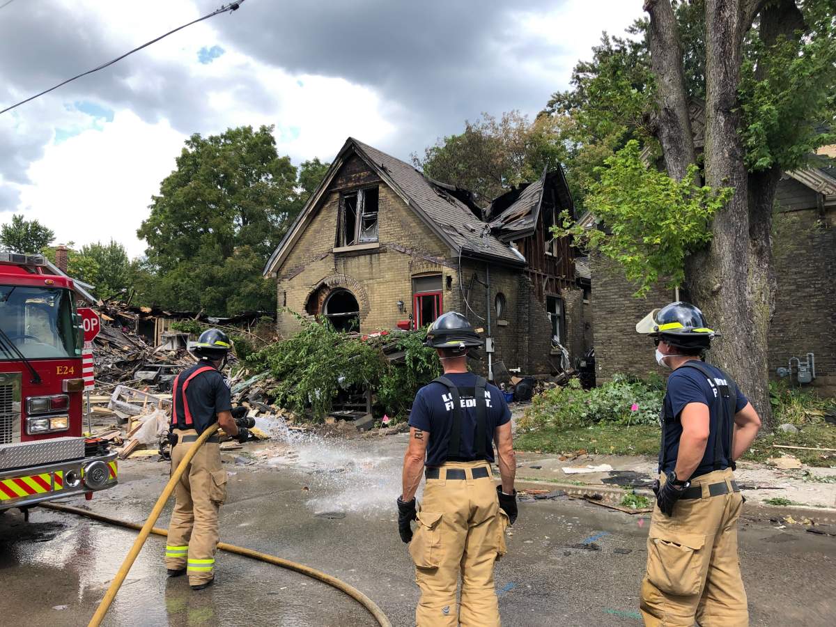 Firefighters in London, Ont., clean the street in front of 448 Woodman Avenue as they prepare the home for demolition.