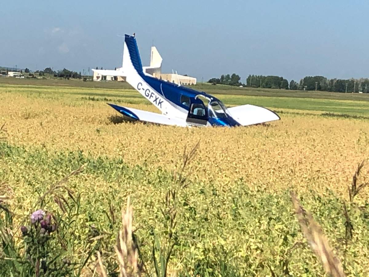 A small airplane is seen nose-down in an Okotoks field following a crash landing.