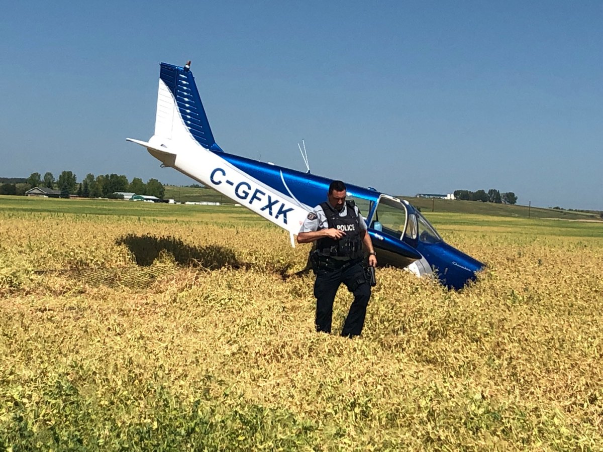 An RCMP officer is seen walking near the site of a small airplane crash in Okotoks, Alta., on Thursday, Aug. 8, 2019. 