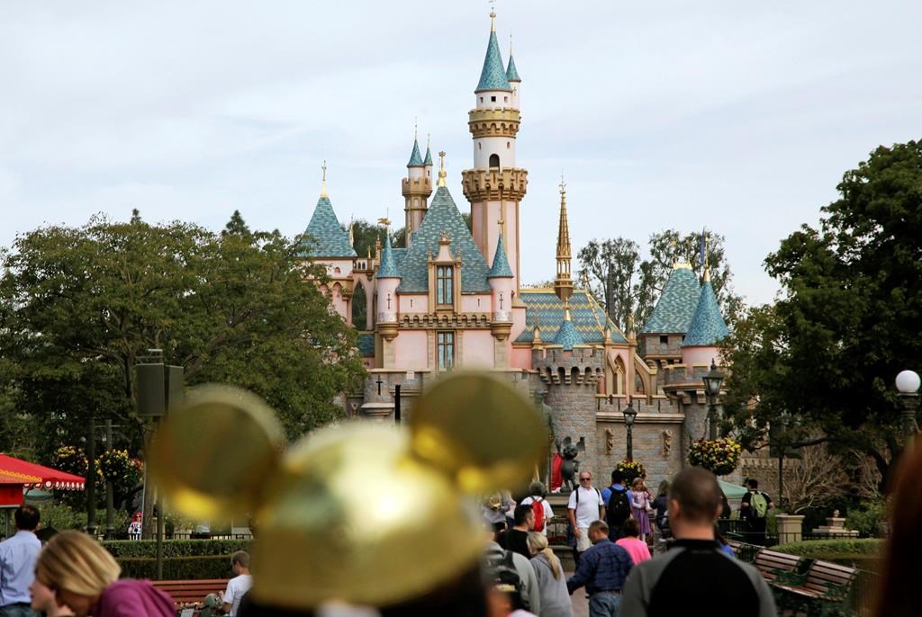 FILE - In this Jan. 22, 2015, file photo, visitors walk toward Sleeping Beauty's Castle in the background at Disneyland Resort in Anaheim, Calif.