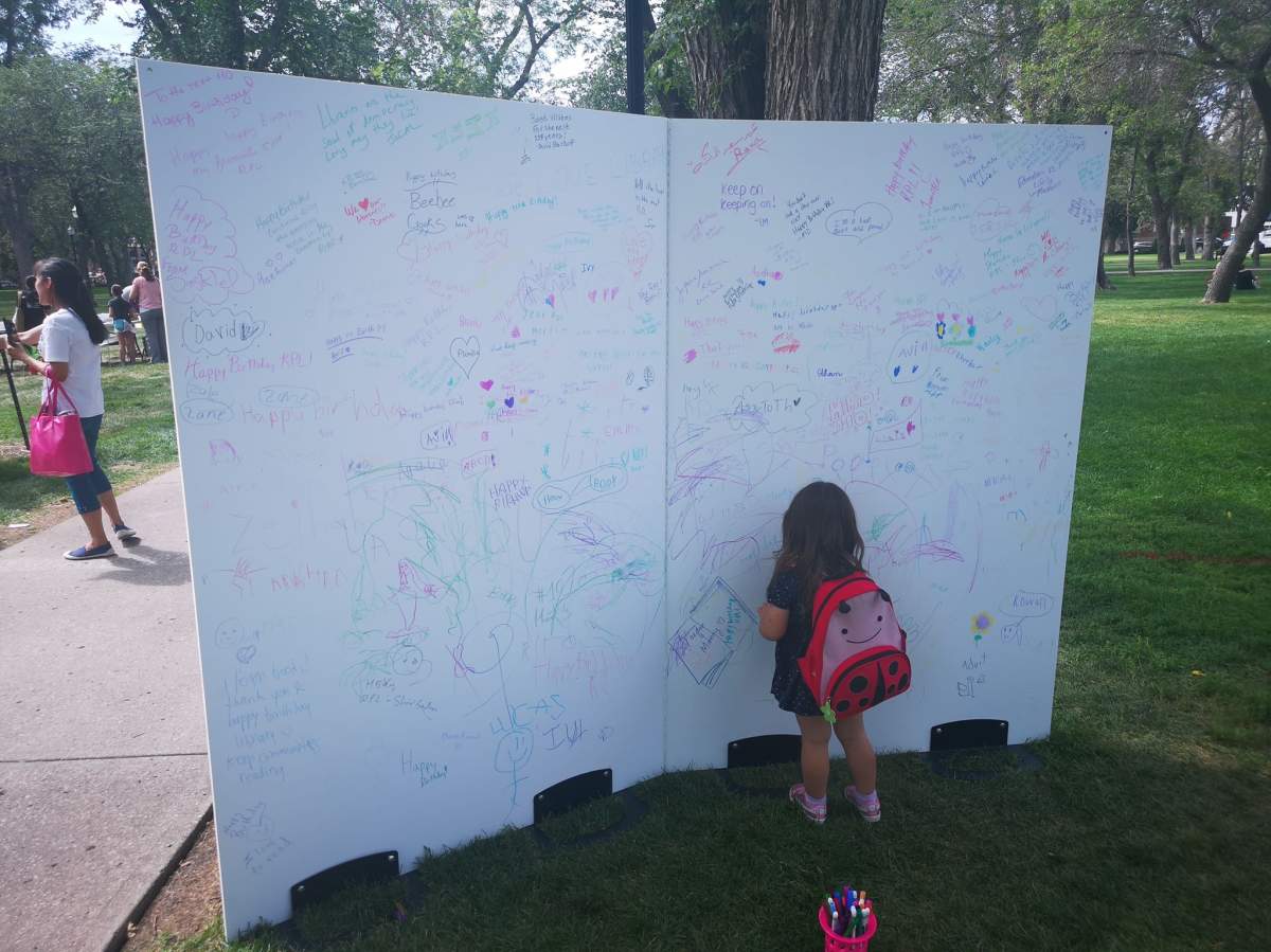 A little girl signed the very large pages of a memorandum at the celebration.