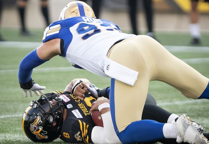 Winnipeg Blue Bombers defensive lineman Craig Roh (93) goes over Hamilton Tiger-Cats quarterback Jeremiah Masoli (8) during first half CFL football game action in Hamilton, Ont. on Friday, July 26, 2019. Masoli was injured on the play. Six of the nine quarterbacks from the opening day of the CFL season have gone down to injury. Ask coaches and QBs what they think of that streak of bad luck and you'll hear a mix of answers. 
