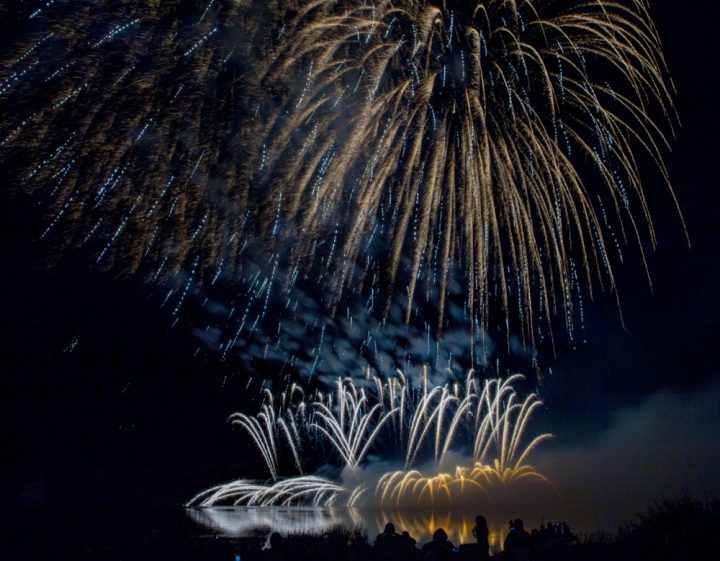 The setting adds to the scene: the reflection of the fireworks on Moosomin Lake is part of the events grandeur.