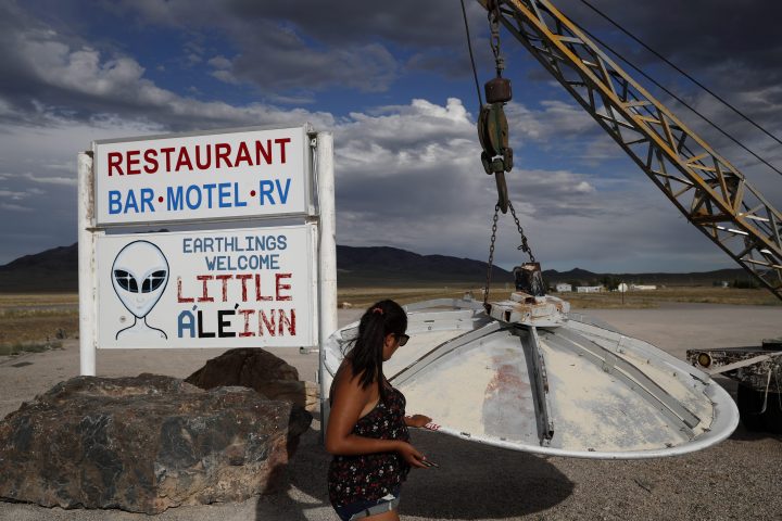 In this July 22, 2019 photo, Grace Capati looks at a UFO display outside of the Little A’Le’Inn, in Rachel, Nev., the closest town to Area 51.