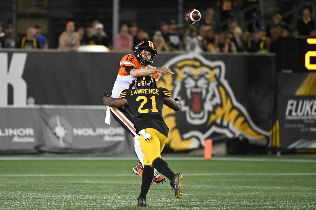 BC Lions quarterback Mike Reilly, 13, gets a throw off before being tackled by Hamilton Tiger-Cats linebacker Simoni Lawrence during second half CFL football game action in Hamilton, Ont., on Saturday, August 10, 2019.