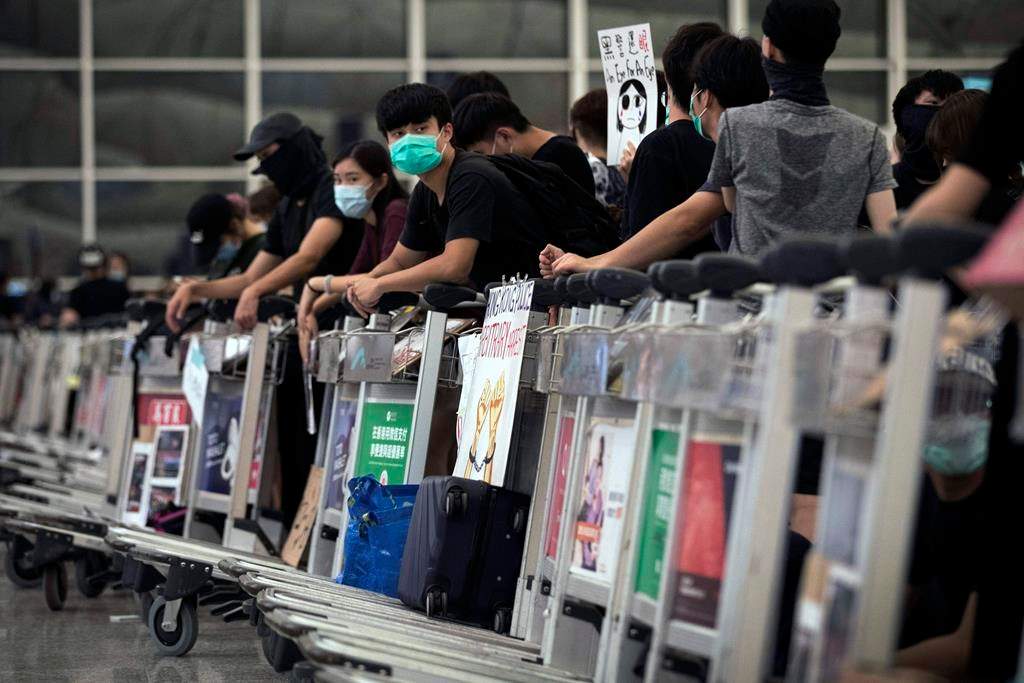 Protesters use luggage trolleys to block the departure gates during a demonstration at the Airport in Hong Kong, Tuesday, Aug. 13, 2019.