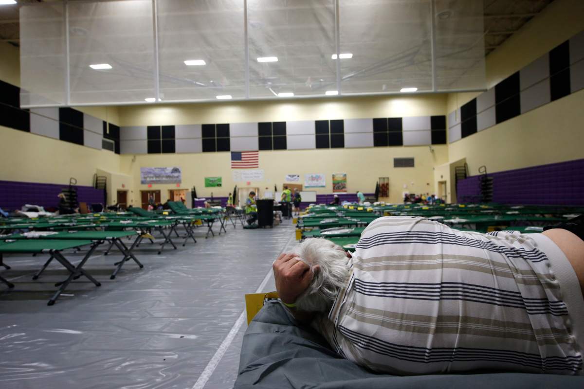 An evacuee lies on a cot at an evacuation shelter for people with special needs, in preparation for hurricane Dorian, at Dr. David L. Anderson Middle School in Stuart, Fla., Sunday, Sept. 1, 2019. Some coastal areas are under a mandatory evacuation since the path of the storm is still uncertain.