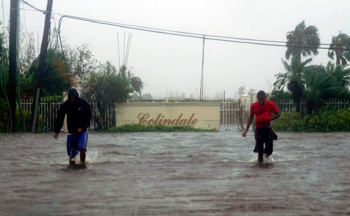 Residents wade through a street flooded with water brought on by Hurricane Dorian in Freeport, Bahamas, Tuesday, Sept. 3, 2019. (AP Photo/Ramon Espinosa)