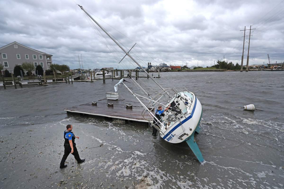 Beaufort Police Officer Curtis Resor, left, and Sgt. Micheal Stepehens check a sailboat for occupants in Beaufort, N.C. after hurricane Dorian passed the North Carolina coast. (The Associated Press)