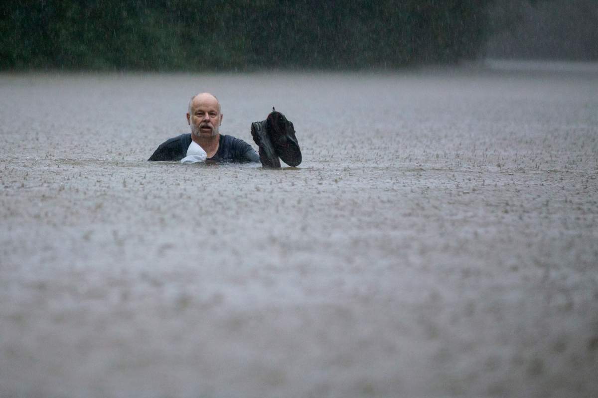 A man wades out through floodwaters caused by heavy rain spawned by tropical depression Imelda inundated the area on Thursday, Sept. 19, 2019, in Patton Village, Texas. (Brett Coomer/Houston Chronicle via AP)