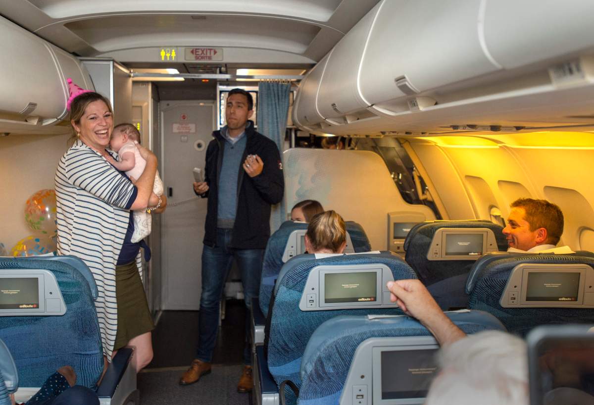 Conservative Leader Andrew Scheer, right, looks on as Press Secretary Dan Schow, centre, leads birthday celebrations for Principal Secretary Kenzie Potter, holding her 9-week-old baby Georgia Hubick, on the campaign plane on Wednesday, Sept. 18, 2019.