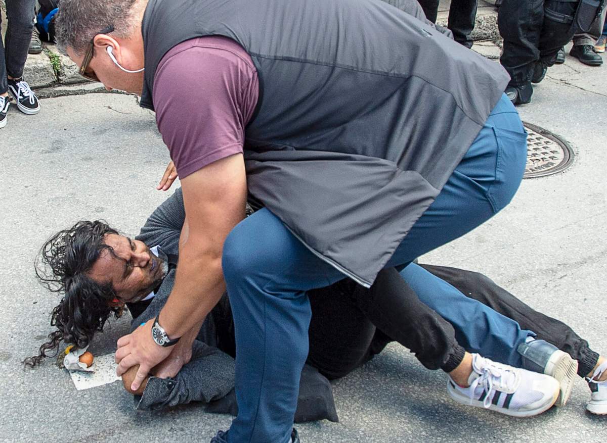 Security detail for Liberal Leader Justin Trudeau hold down a protester carrying eggs as the Liberal leader takes part in the climate strike in Montreal on Friday, Sept. 27, 2019.