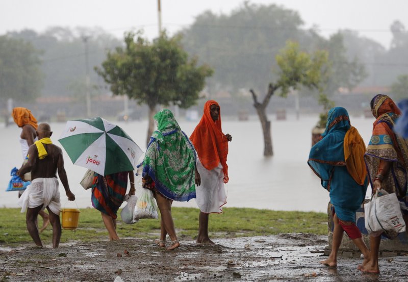 Hindu devotees return home in the rain after offering rituals in the River Ganges in Prayagraj, in the northern Indian state of Uttar Pradesh, Saturday, Sept. 28, 2019.