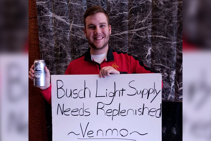 Carson King, 24, holds up a beer and the sign that won him viral fame at a University of Iowa football game.