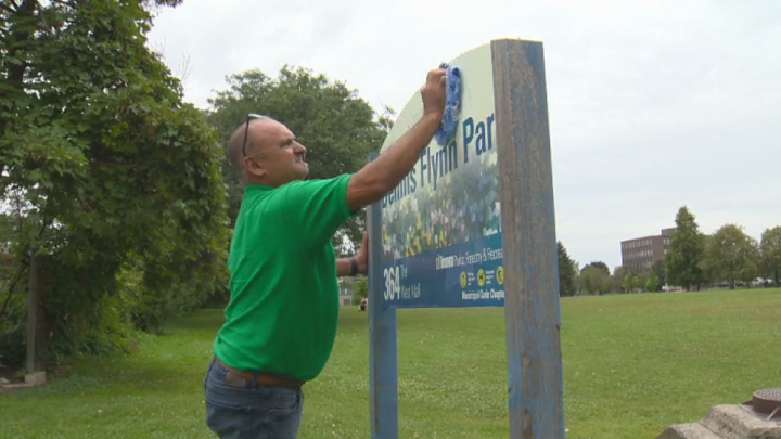A man cleans a sign at Dennis Flynn Park after anti-Muslim graffiti was found on it Sunday.
