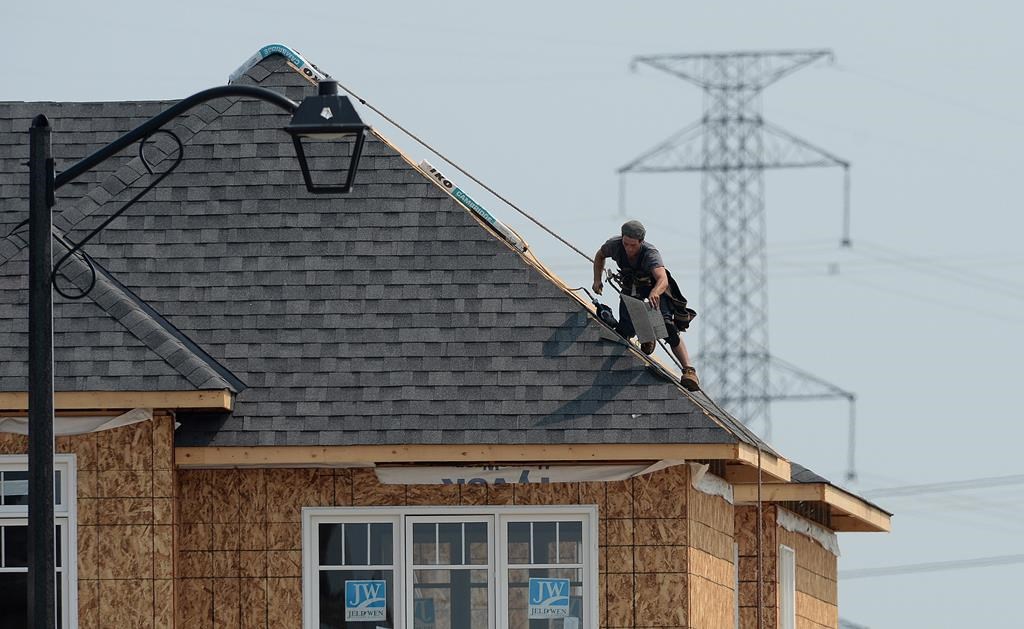 A construction worker shingles the roof of a new home in a housing development in Ottawa on Monday, July 6, 2015.