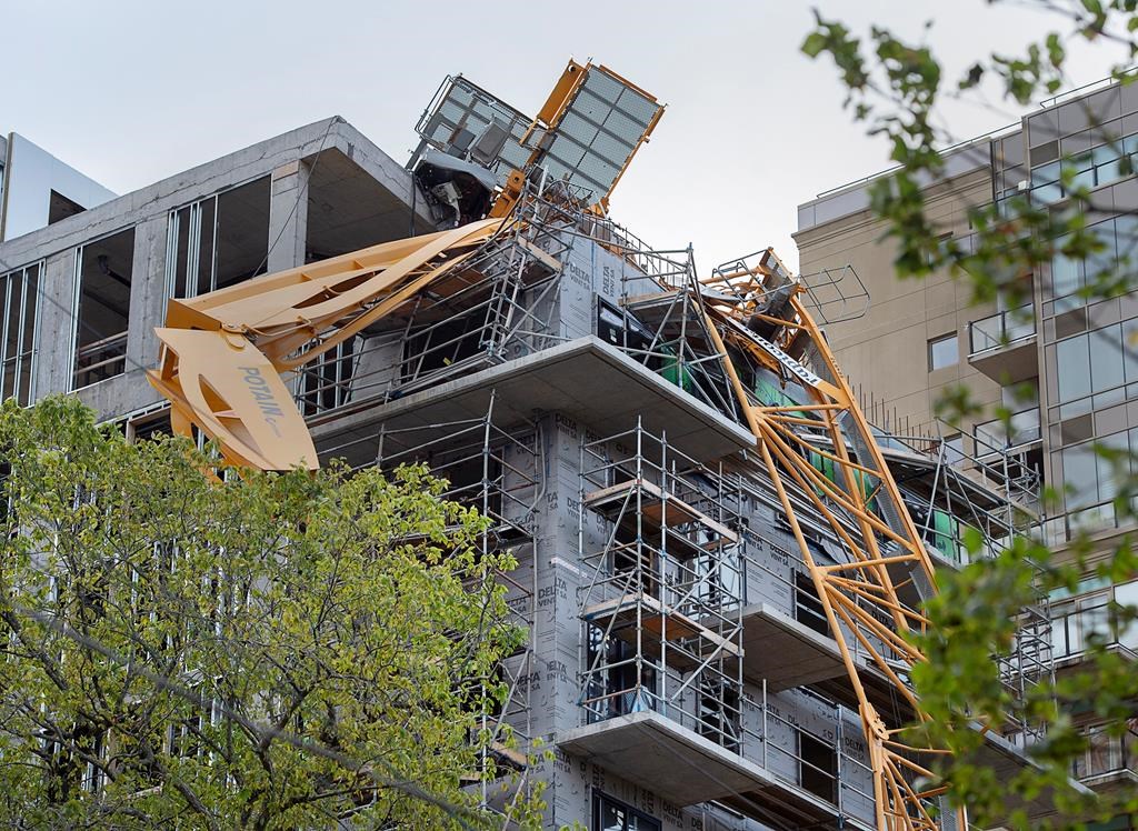 A toppled building crane is draped over a new construction project in Halifax on Sunday, Sept. 8, 2019. The Nova Scotia government says it is too soon to say who will pay the costs to remove a construction crane blown down during post-tropical storm Dorian. THE CANADIAN PRESS/Andrew Vaughan