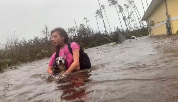 Julia Aylen wades through waist-deep water carrying her pet dog as she is rescued from her flooded home during hurricane Dorian in Freeport, Bahamas, Tuesday, Sept. 3, 2019.
