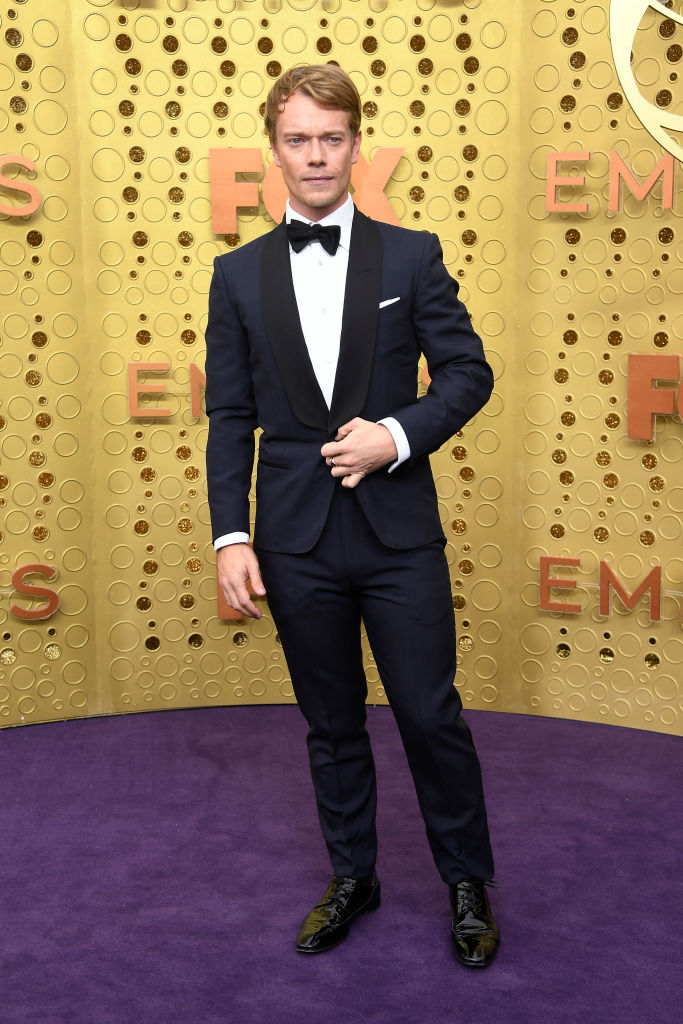 Alfie Allen looked smart in a tailor navy blue suit.