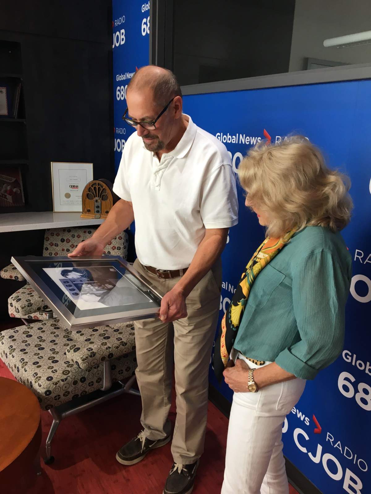 Barbara Berg and Geoff Currier look at a photo of her father, 680 CJOB founder Jack Blick.