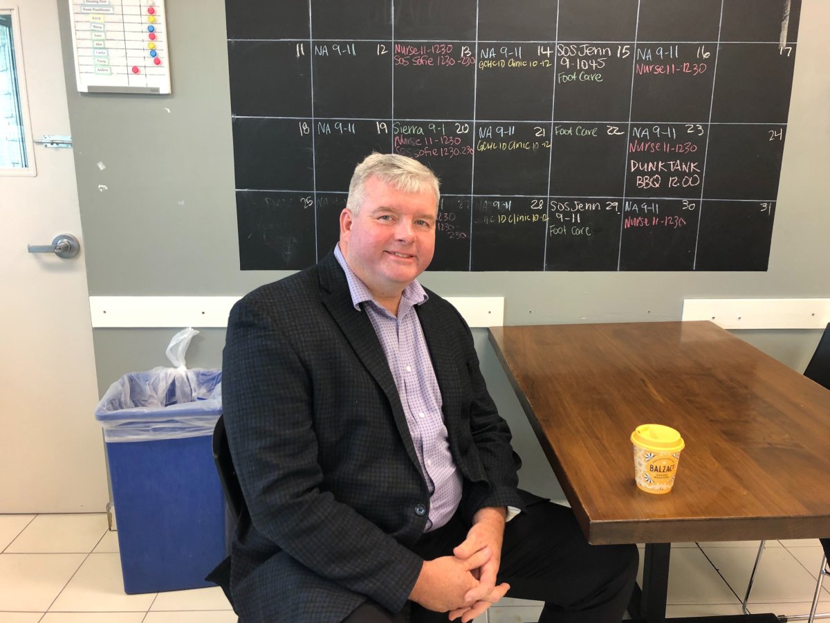 Tom Gill with the Guelph chapter of 100 Men Who Give a Damn sits at one of the Drop-In Centre’s new tables that was among the furniture purchases following a $13,000 contribution.