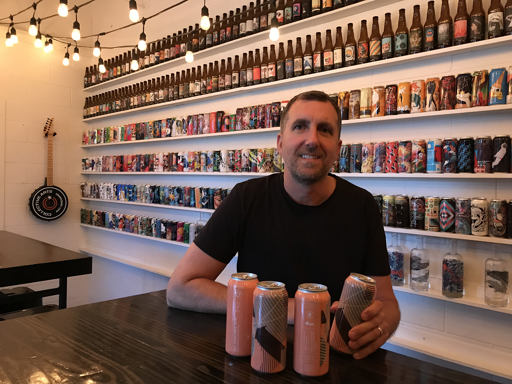 Collective Arts Brewing CEO Matt Johnston sits with cans of 'All Together Now', a collaborative effort with MERIT Brewing in Hamilton.