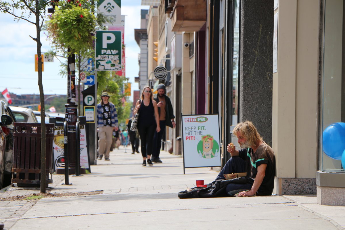A homeless man sitting on a George Street sidewalk eats a sandwich.  A local store owner, as well as Peterborough Police, have confirmed the homeless issue in Peterborough negatively impacts public perception of downtown safety. 