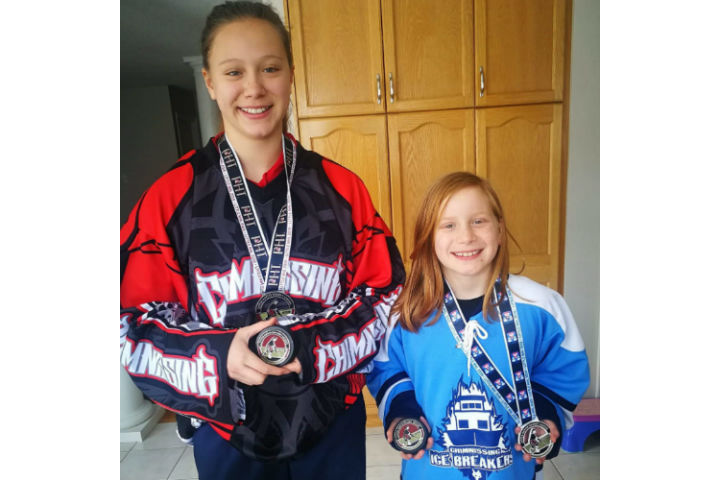 Emily Vanderstelt, 15, and Holly Vanderstelt, 9, wearing their Chimnissing jerseys and hockey medals. The sisters previously received equipment through the hockey drive.