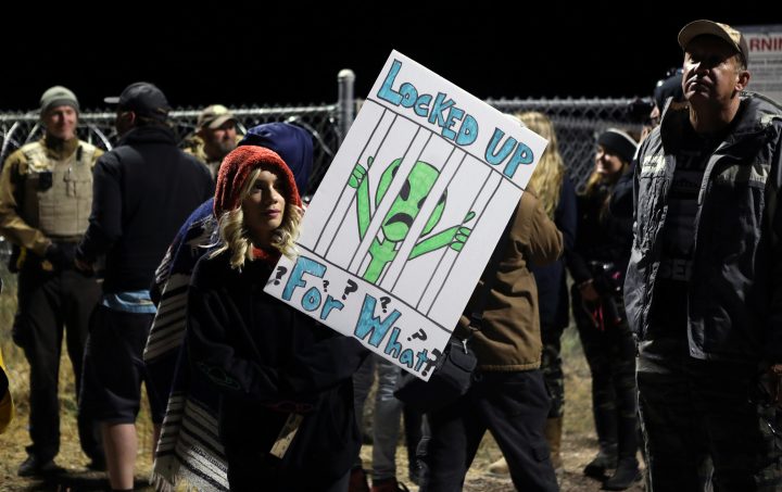 A woman carries a sign outside a gate to Area 51 on Sept. 20, 2019.