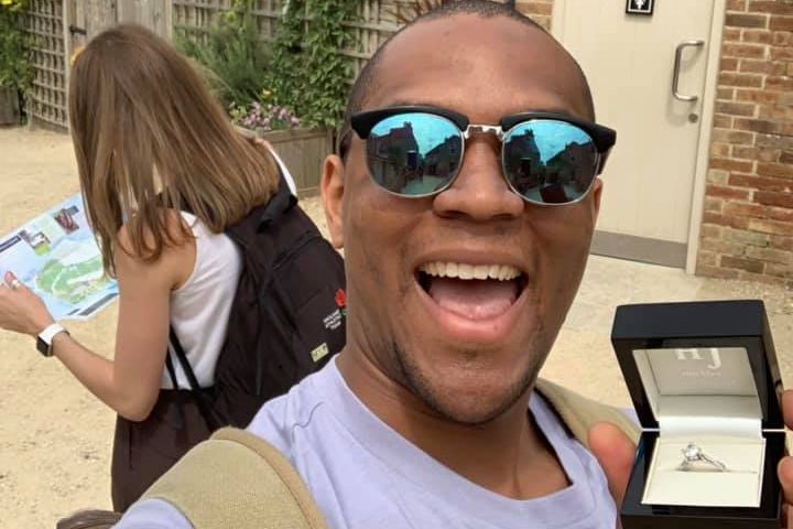 Edi Okoro holds an engagement ring behind girlfriend Cally Read‘s back.