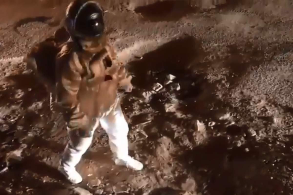 An actor in a spacesuit is shown walking across a pothole-riddled road in Bengaluru, India, in this image from video posted Sept. 1, 2019.