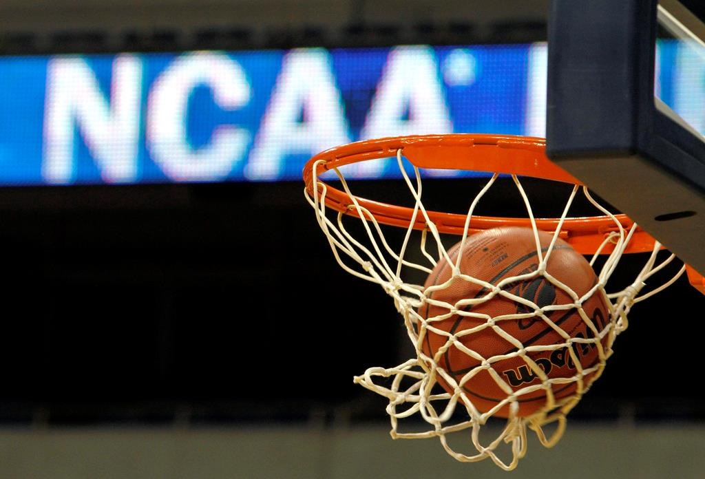 FILE - In this March 20, 2010, file photo, a ball flicks through the net in front of the NCAA logo on the marquis during an NCAA college basketball practice in Pittsburgh. Defying the NCAA, California's governor signed a first-in-the-nation law Monday, Sept. 30, that will let college athletes hire agents and make money from endorsements — a move that could upend amateur sports in the U.S. and trigger a legal challenge. (AP Photo/Keith Srakocic, File).