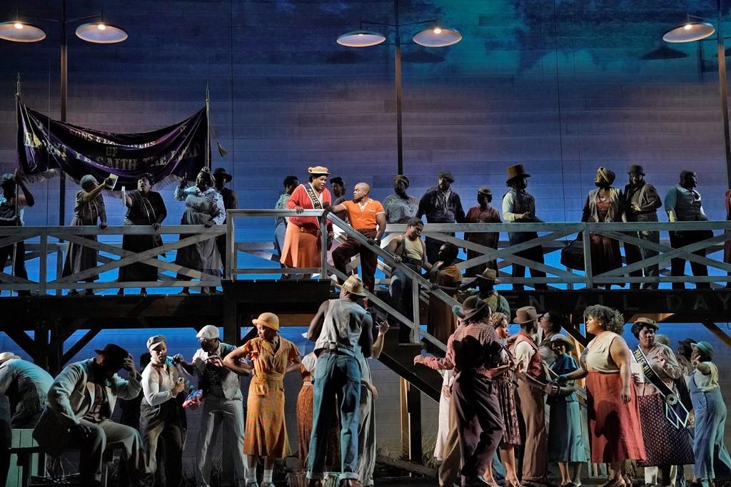 This image released by the Metropolitan Opera shows Latonia Moore as Serena, center left on stairs, and Frederick Ballentine as Sportin' Life in a scene from the Gershwins' "Porgy and Bess." (Ken Howard/Met Opera via AP).