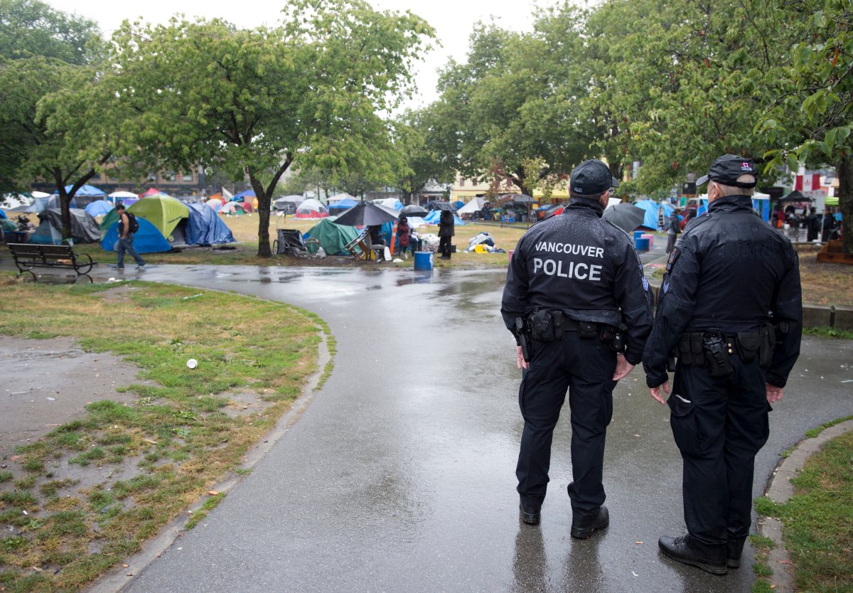 Vancouver police officers watch over tent city at Oppenheimer park in downtown Vancouver, Wednesday, August, 21, 2019. 