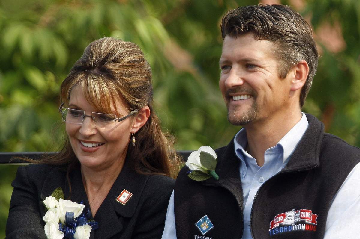 Former Alaska governor Sarah Palin holds her husband Todd's hand as newly sworn-in Gov. Sean Parnell gives his acceptance speech during a ceremony in Fairbanks, Alaska, on July 26, 2009.