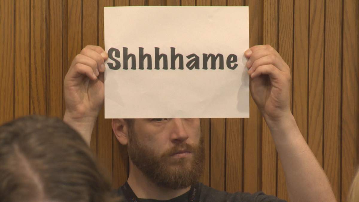 Millennium For All member Andrew Kohan holds a sign at city hall to protest ongoing security screening at the Millennium Library.