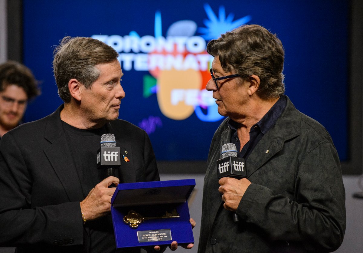 Toronto Mayor John Tory, left, presents Robbie Robertson with a key to the city during a TIFF press conference in Toronto on Thursday.