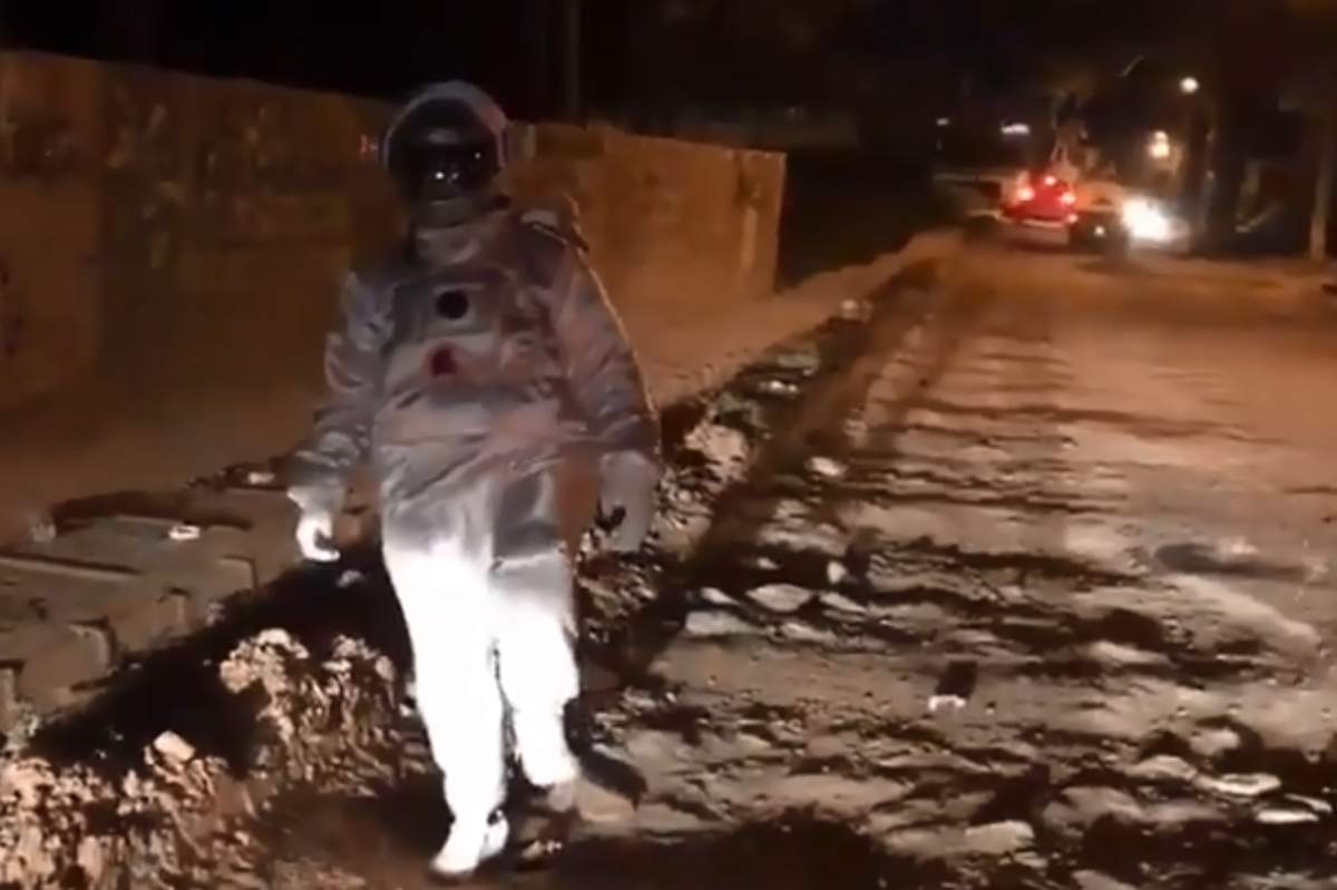 An actor in a spacesuit is shown walking across a pothole-riddled road in Bengaluru, India, in this image from video posted Sept. 1, 2019.