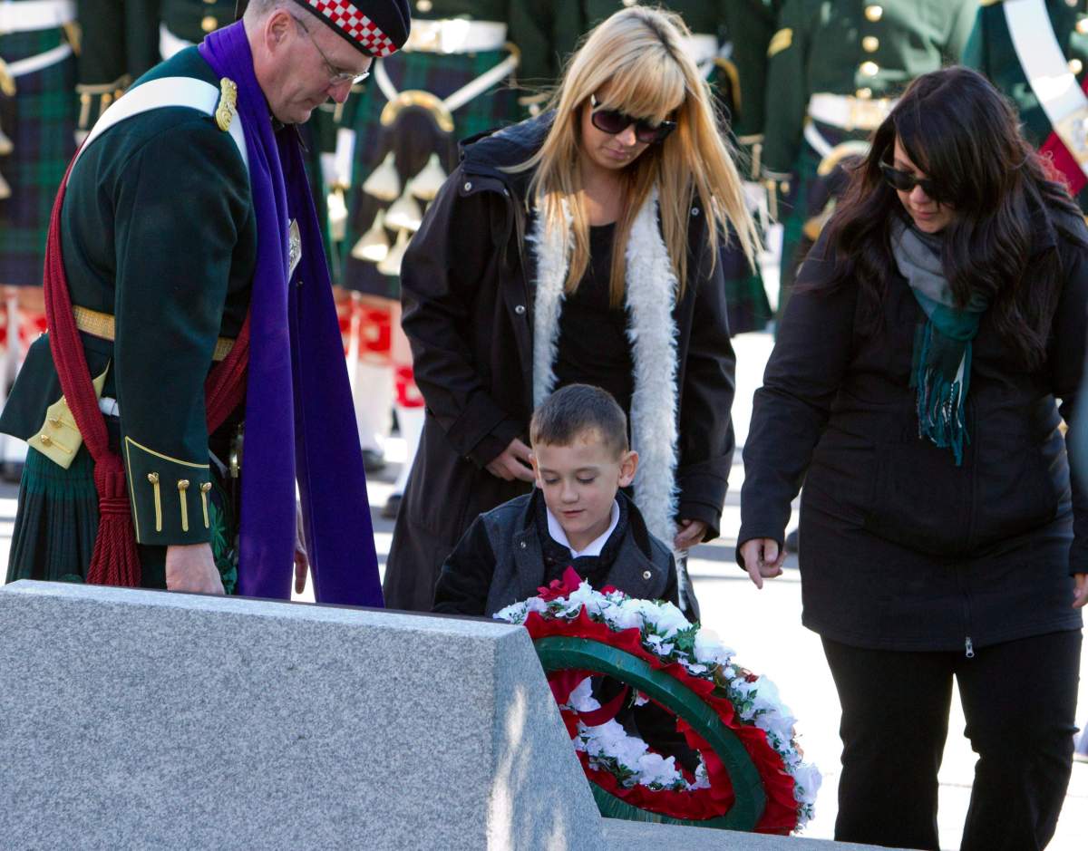 Cpl. Nathan Cirillo's sisters look on as Cirillo's son Marcus places a wreath at a memorial plaque on the one year anniversary of his death.
