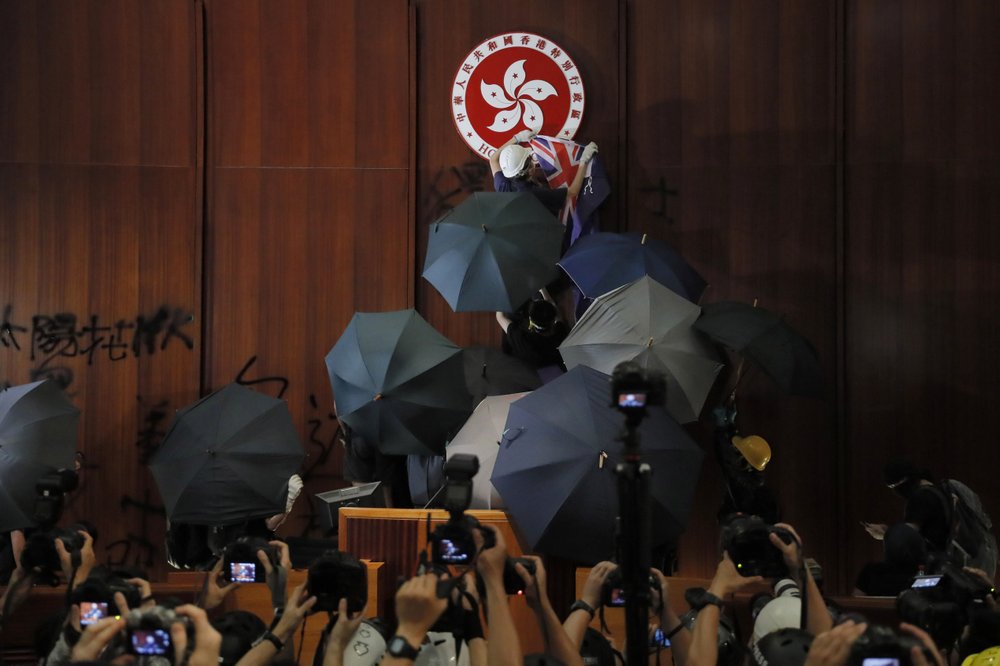 FILE - In this July 1, 2019, file photo, a protester covers the Hong Kong emblem with a Hong Kong colonial flag after they broke into the Legislative Council building in Hong Kong. Hong Kong authorities on Wednesday, Oct. 23, 2019 withdrew an unpopular extradition bill that sparked months of chaotic protests that have since morphed into a campaign for greater democratic change.