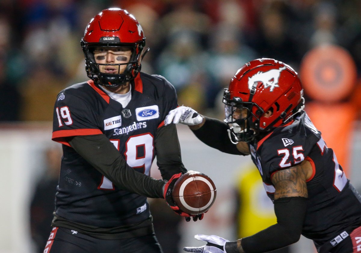 Calgary Stampeders quarterback Bo Levi Mitchell, left, hands the ball off to Don Jackson during first half CFL football action against the Saskatchewan Roughriders in Calgary, Friday, Oct. 11, 2019.