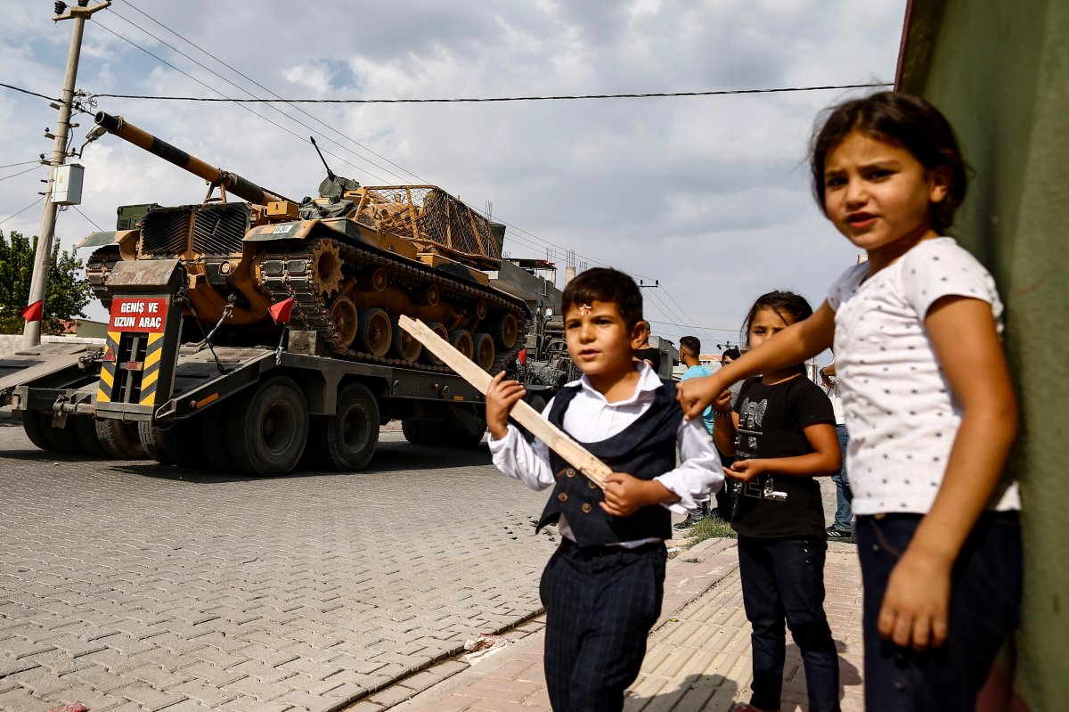Children watch as army tanks are transported on trucks in the outskirts of the town of Akcakale, in Sanliurfa province, southeastern Turkey, at he border of Syria, Thursday, Oct. 17, 2019.