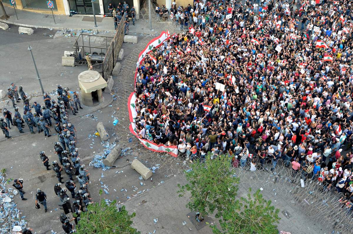 Protesters carry Lebanese flags as they shout anti-government slogans during a protest in downtown Beirut, Lebanon, 19 October 2019.