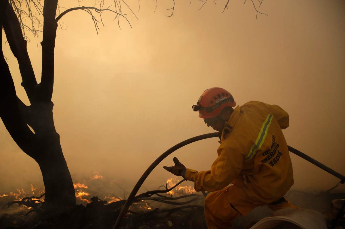 A member of the Los Angeles Sheriff’s Dept. walks on top of a ridge as a wildfire approaches the backyard of a home Thursday, Oct. 24, 2019, in Santa Clarita, Calif.