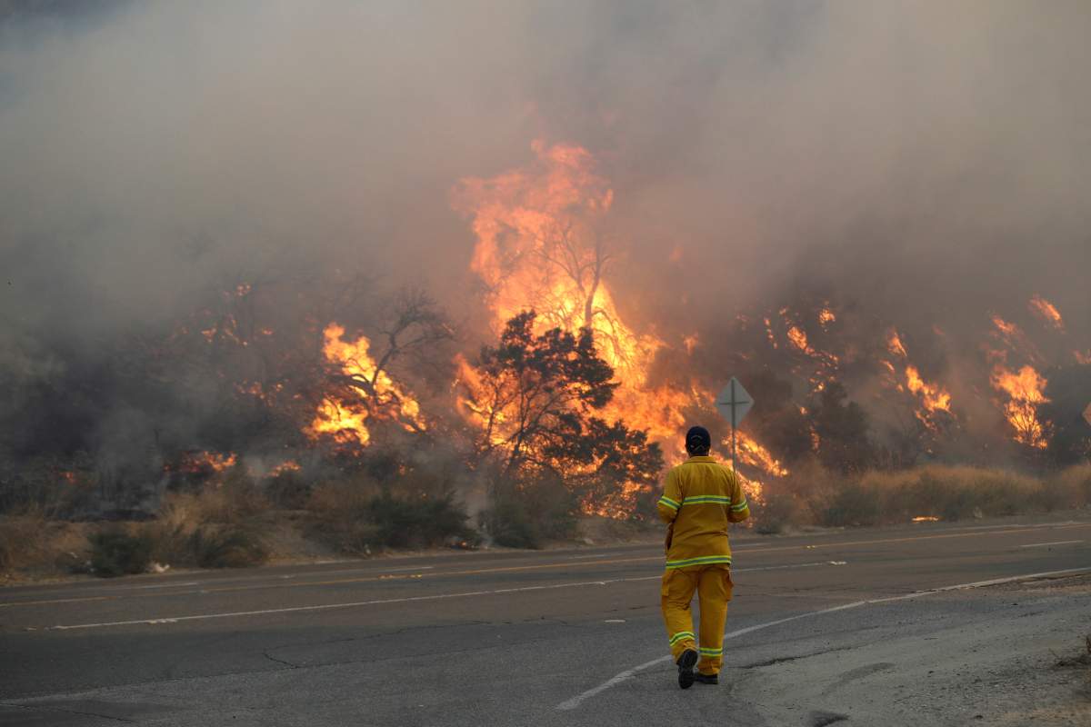 A member of the news media watches flames from a wildfire along Sierra Highway Thursday, Oct. 24, 2019, in Santa Clarita, Calif.